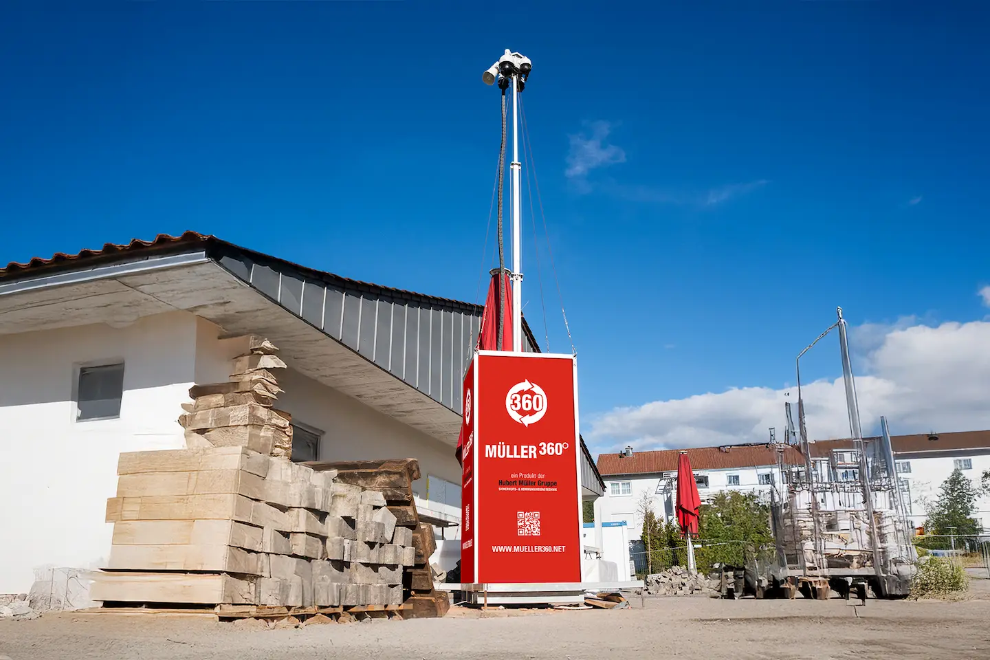 Mobiler Videoturm mit mehreren Überwachungskameras auf einer Baustelle neben gelagerten Baumaterialien